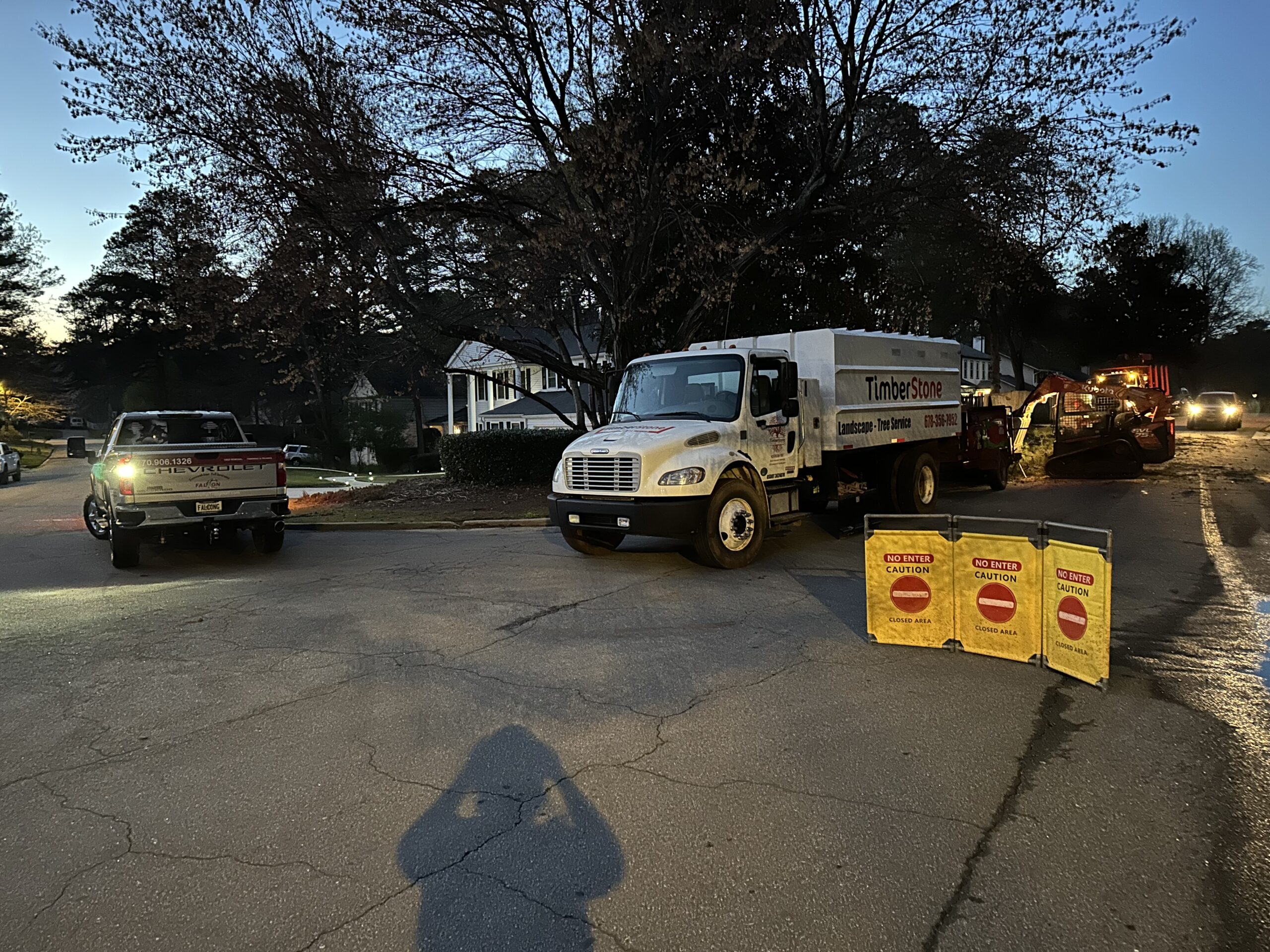 Branded Timberstone box truck on a residential street at dusk with road-closed caution barricades set out