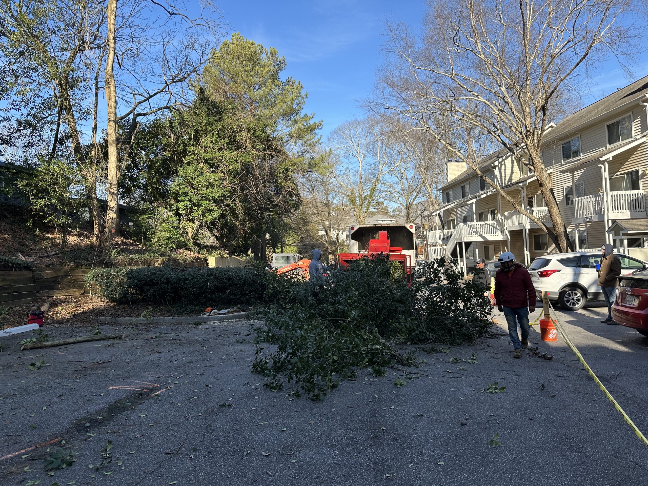 Multi-family apartment property in winter with brush piles staged, crew and equipment working the lot